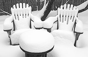 Yard covered in snow with furniture buried under snow