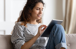 ai_300x195_gen_whatsthedifference Woman sitting on sofa looking at iPad