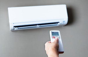 ai_ac_ductless Hand using remote to adjust ductless AC