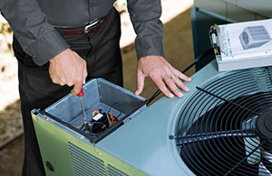 Tech repairing an AC unit