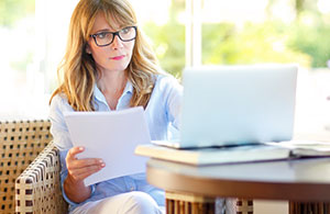 Woman reviewing documents and looking at laptop