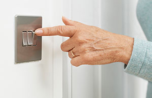 Person's hand pressing switch on wall