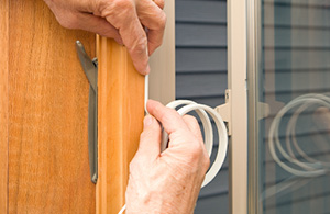 Person adding weather stripping to window